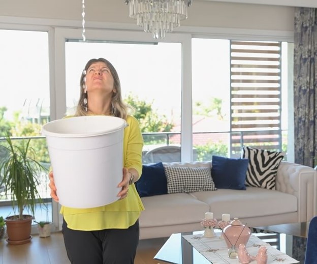 woman with a bucket under a leaking roof