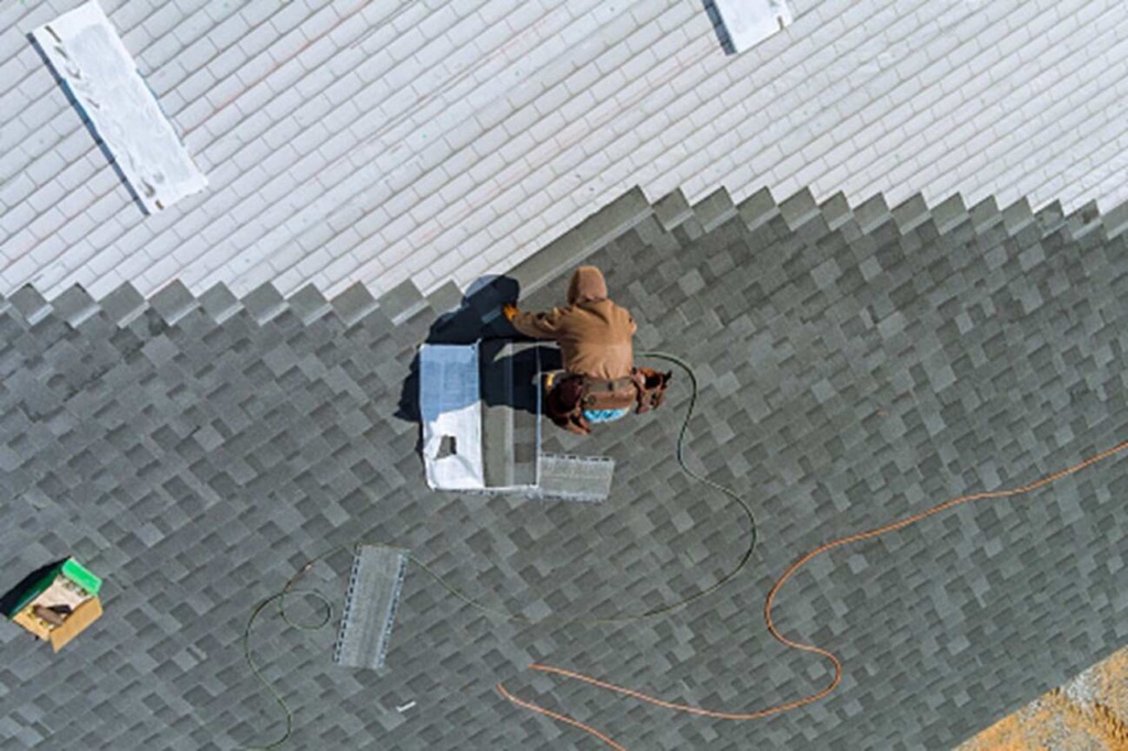 A man is seen repairing a commercial roof in Gresham, OR